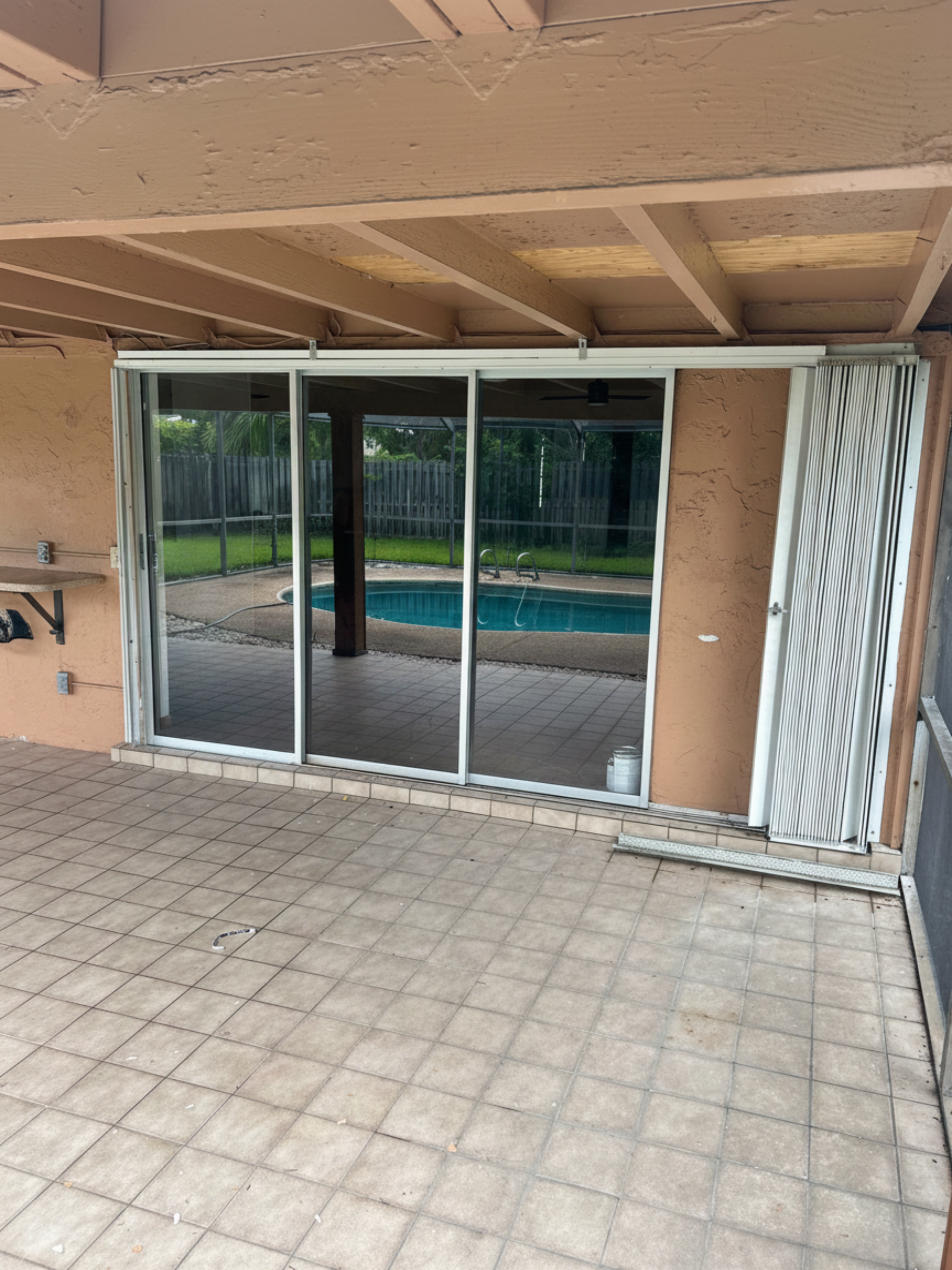 Wide impact sliding glass doors opening to a backyard pool patio
