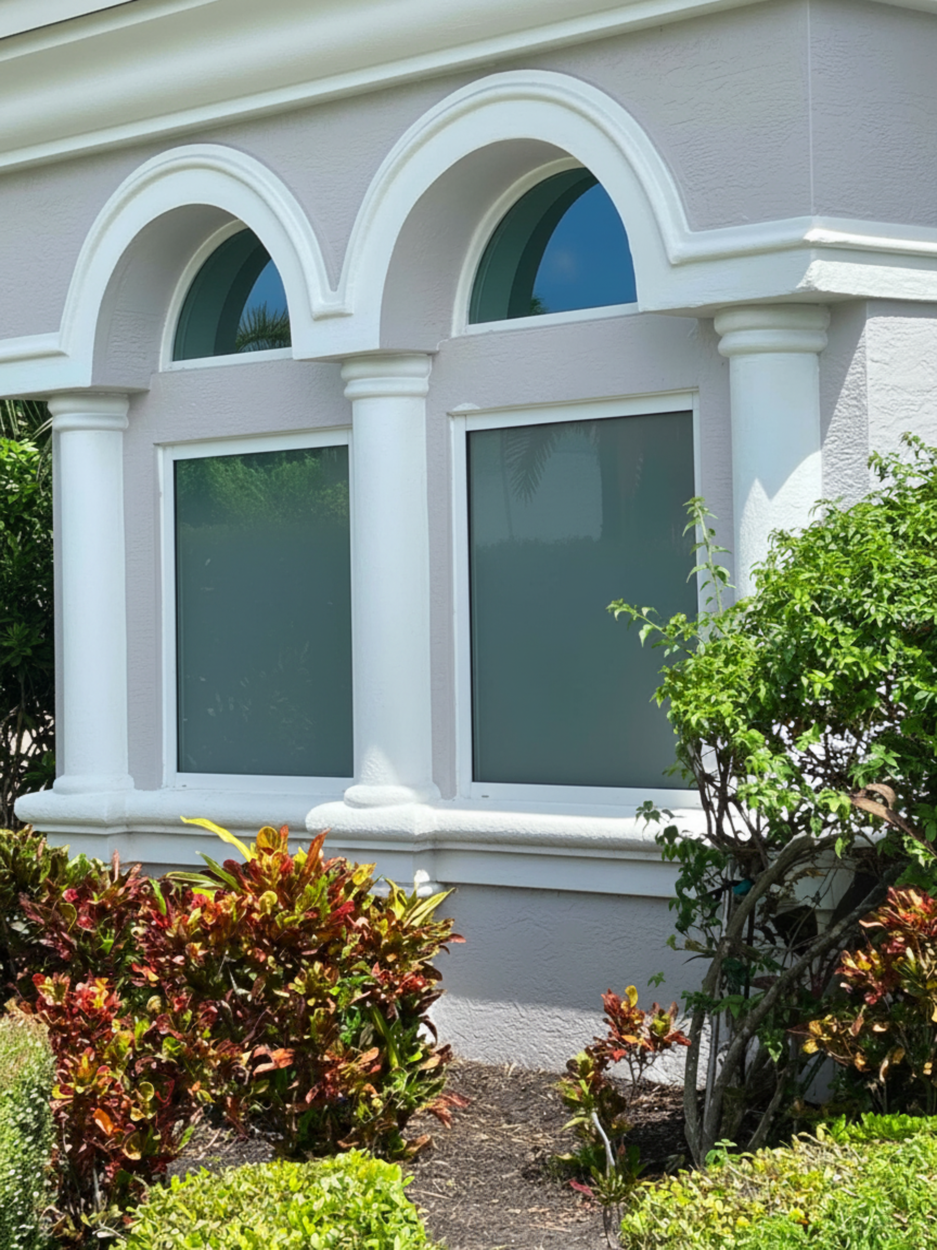 Impact arched windows installed on a South Florida home with tropical landscaping